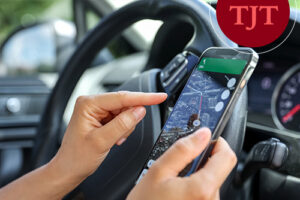 Smartphone displaying an unknown AirTag tracker alert inside a vehicle