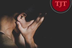 Distressed person holding their head in their hands in a dark room, representing the impact of domestic violence and restraining order cases in NJ